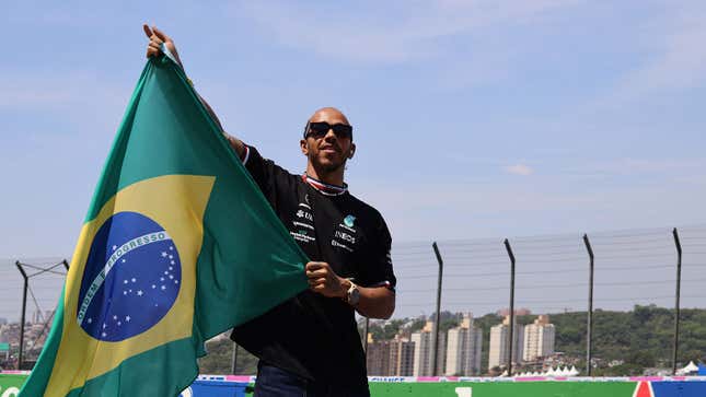 Uma foto de Lewis Hamilton agitando uma bandeira brasileira. 